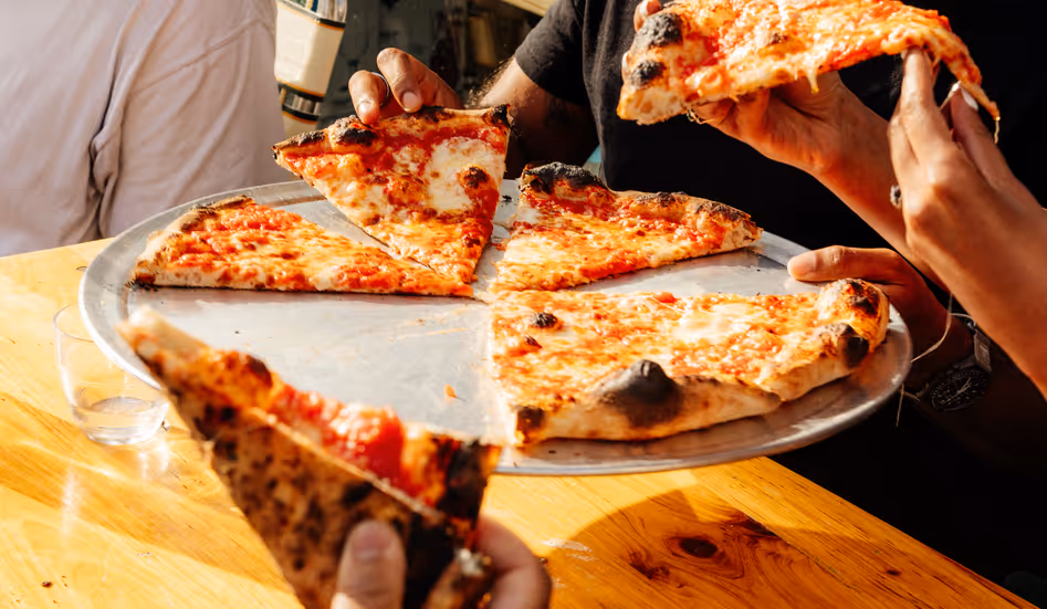 People picking up slices of pizza