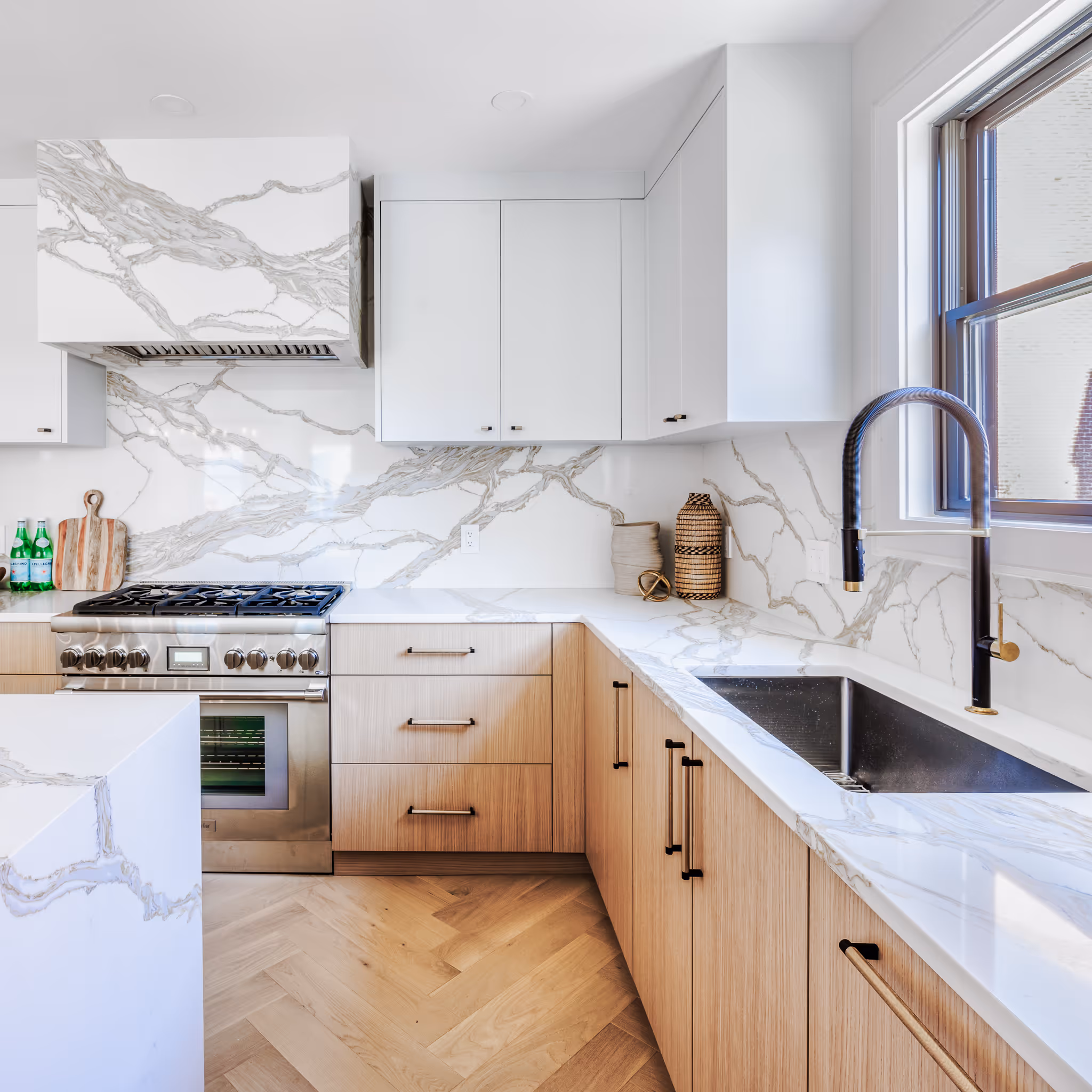 Bright white kitchen with wood cabinets and marble backsplash – real estate photo