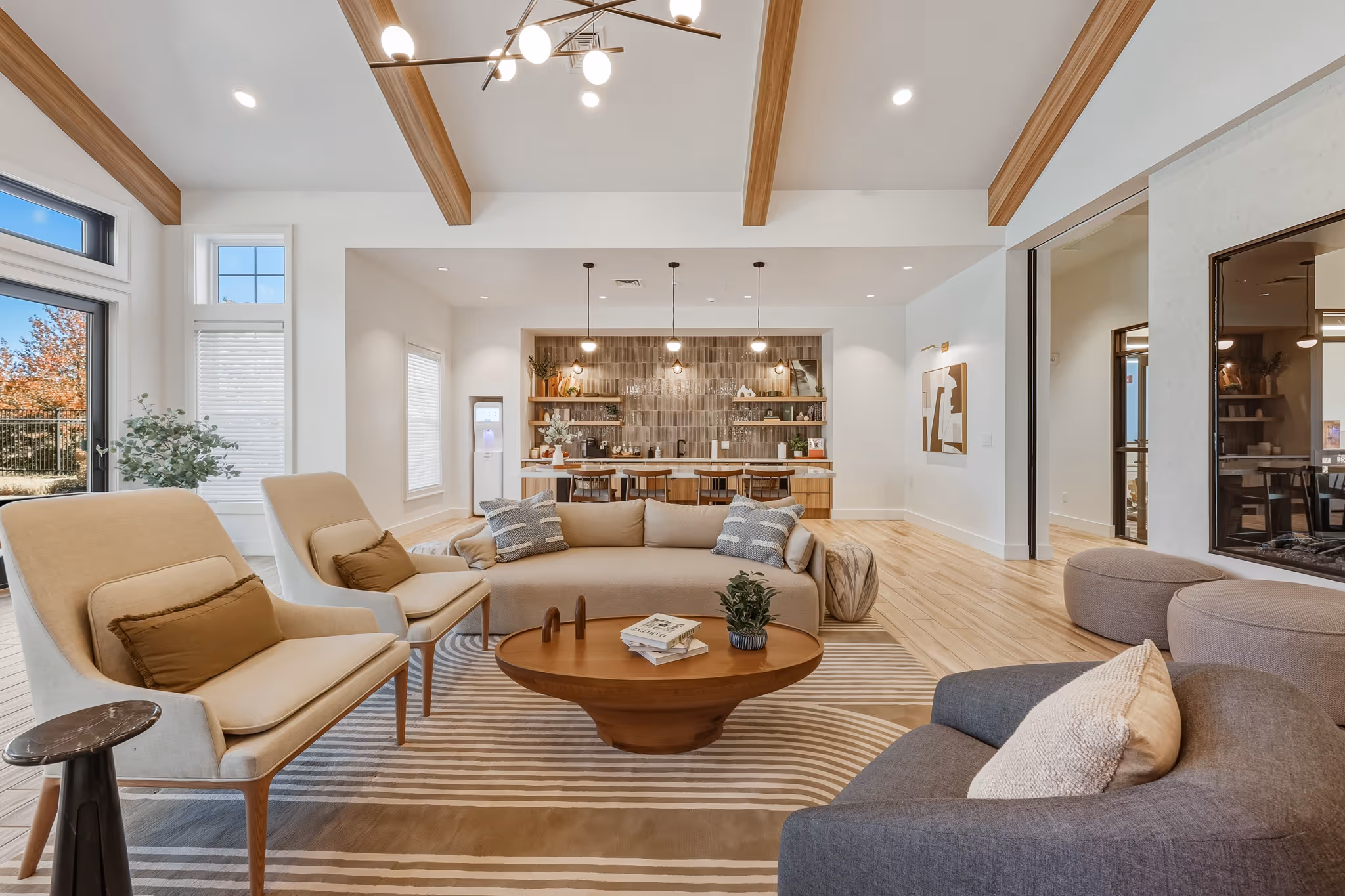 Bright living room with wood beams, seating area, and fireplace.
