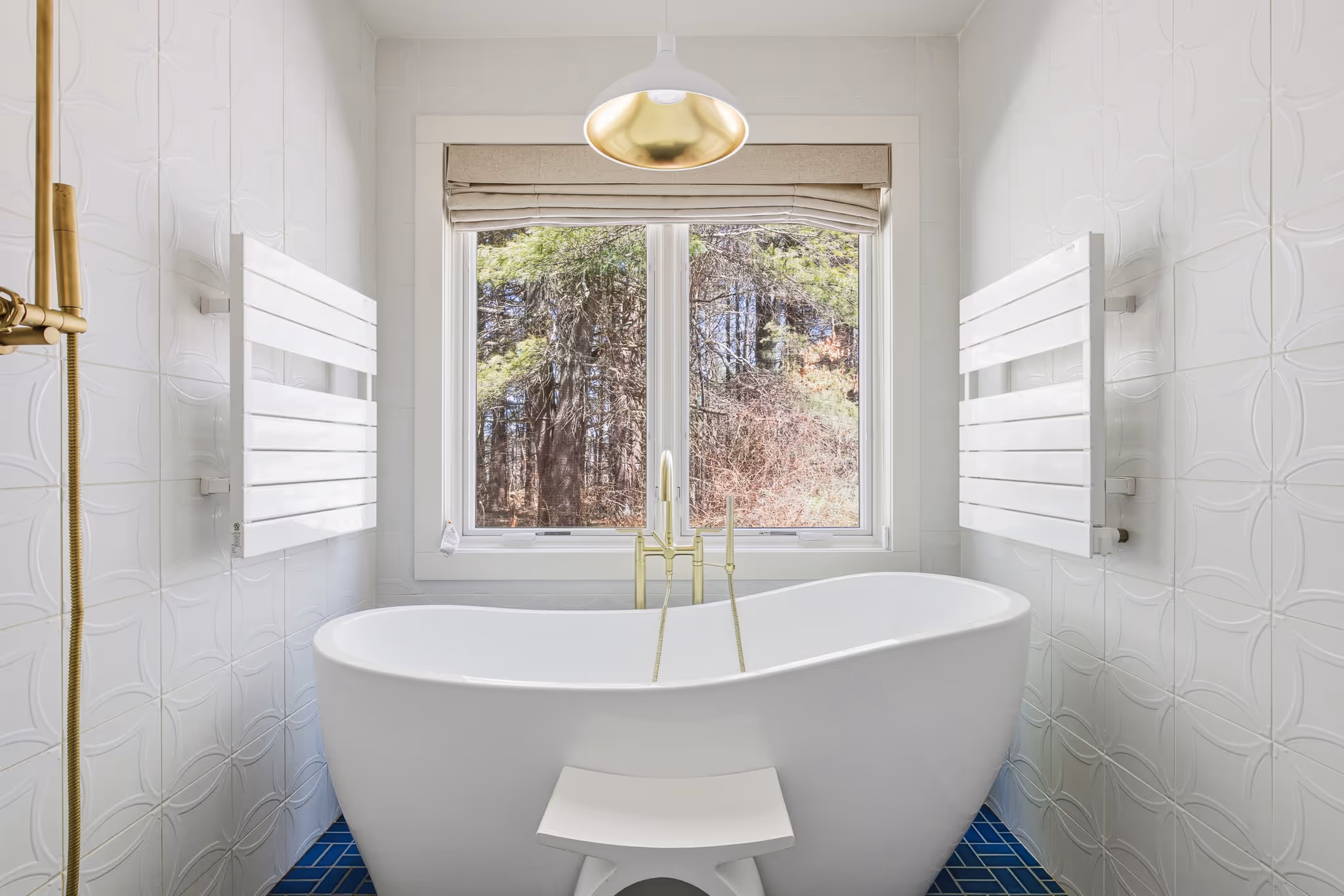 Freestanding bathtub under a large window with natural light.