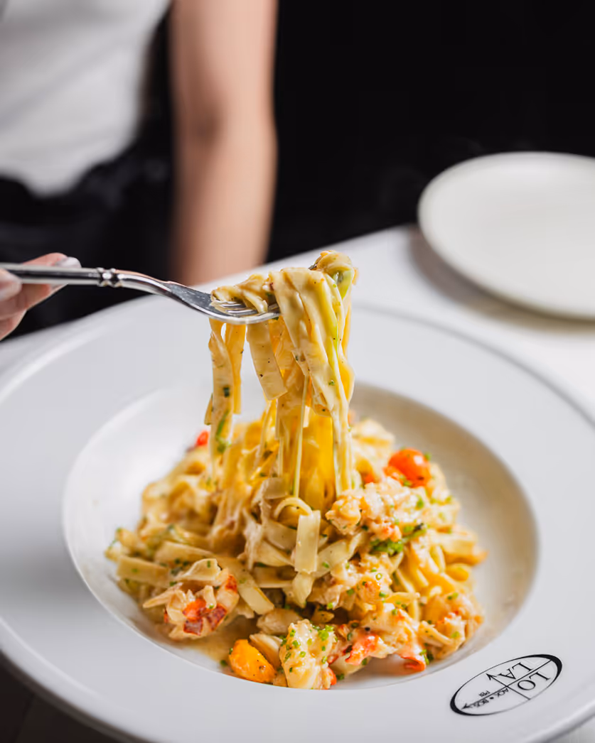 Close-up food photography of creamy pasta dish being twirled on a fork, shot by Boston restaurant photographer.