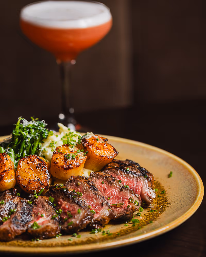 steak plate with a red cocktail in a martini glass