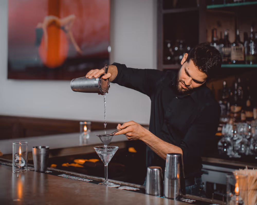 bartender behing the bar puring a cocktail