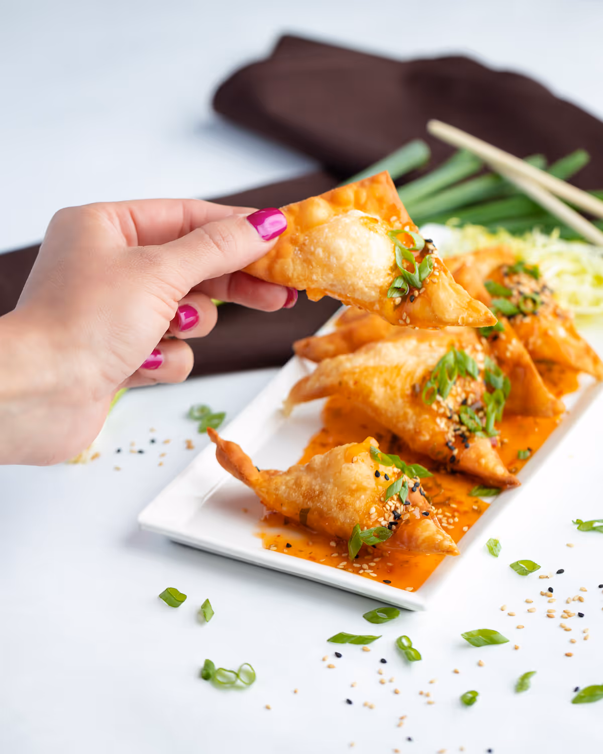 guest grabbing a king crab rangoon from a plate