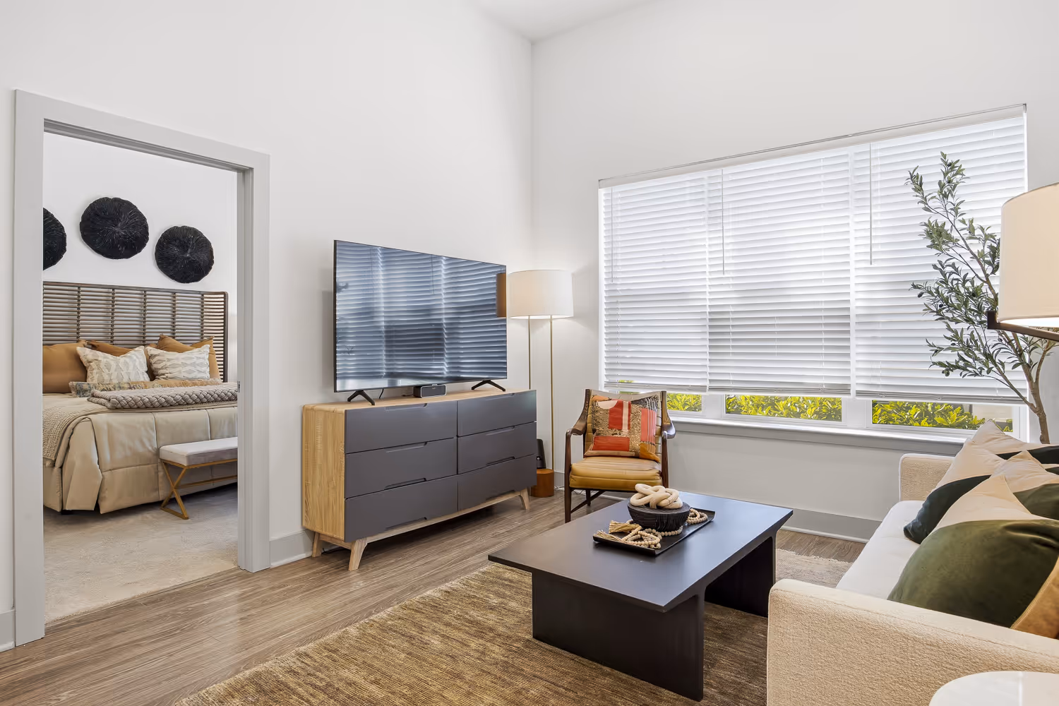 Living room with a wide window, TV console and neutral modern furniture.