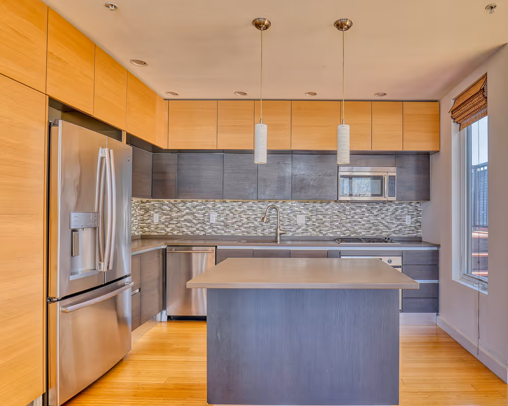 Kitchen before renovation with original cabinets, island and stainless steel appliances in South Boston condo
