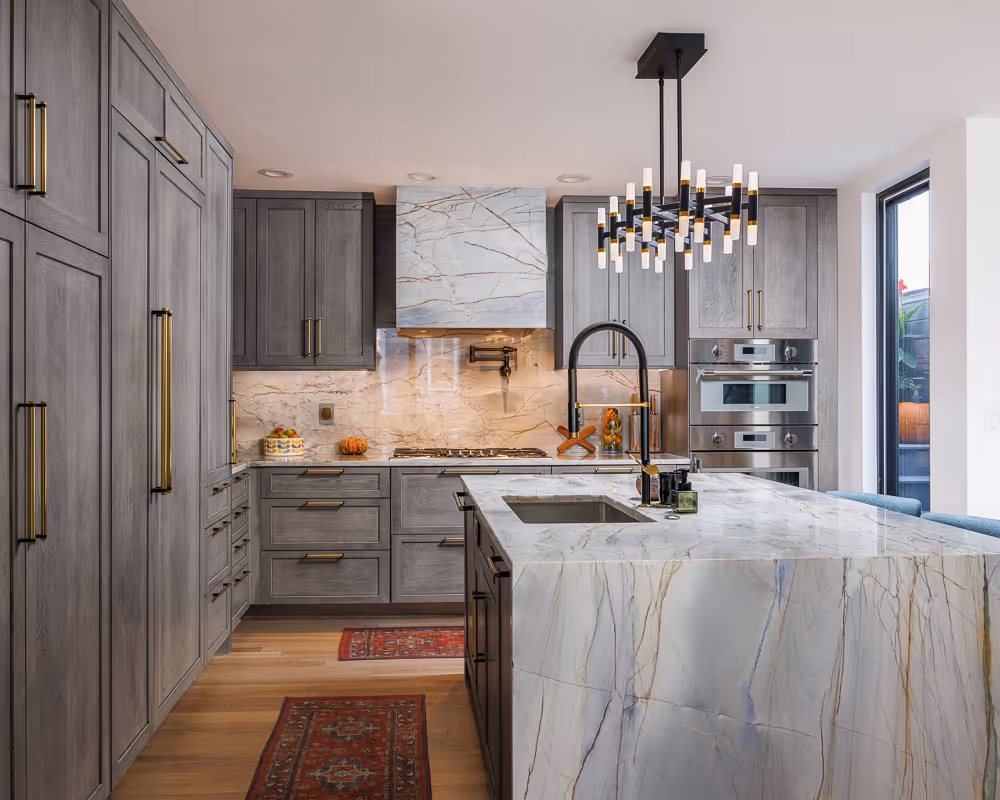 Finished kitchen with custom cabinetry, marble counters, modern lighting and a complete redesign