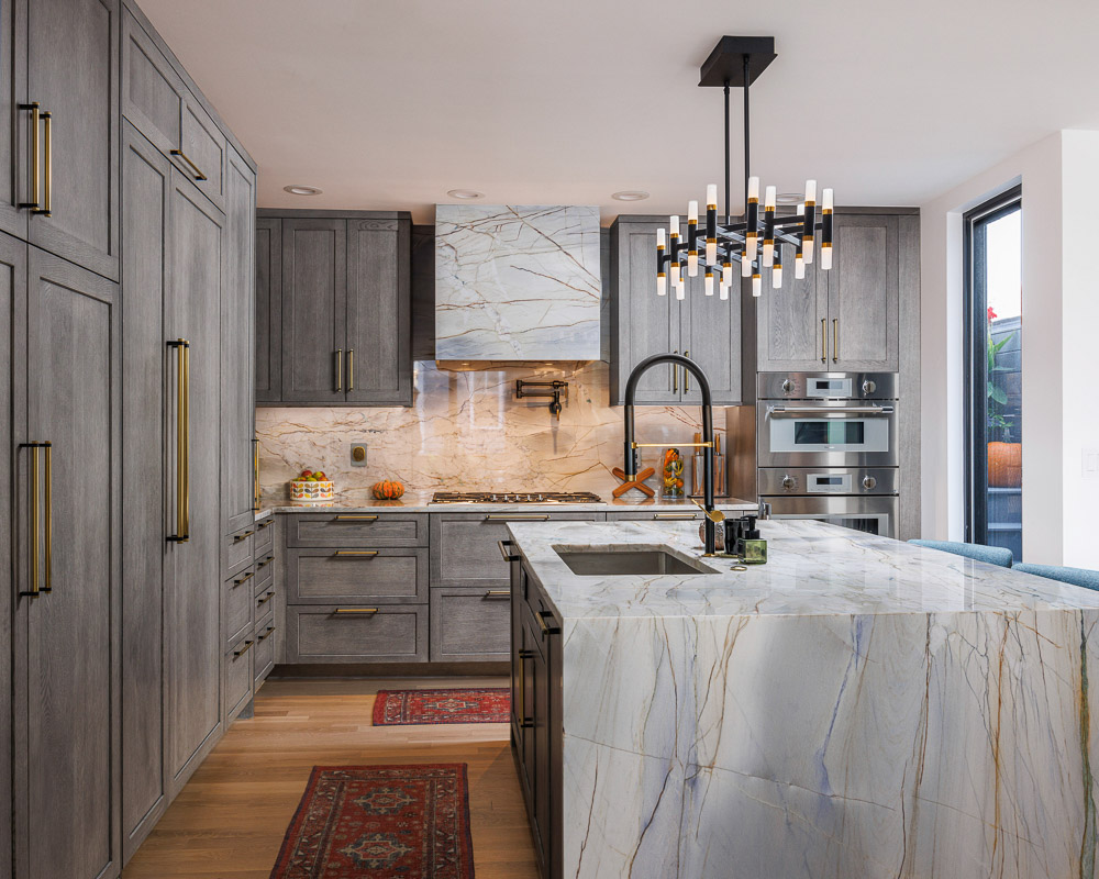Finished kitchen with custom cabinetry, marble counters, modern lighting and a complete redesign