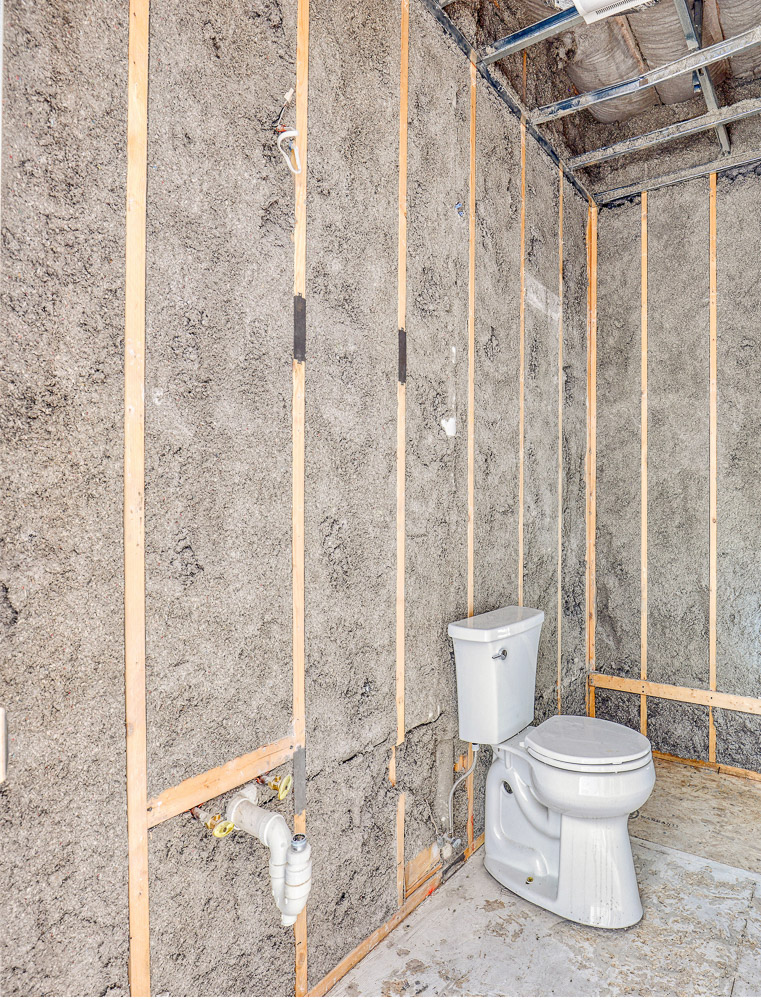 Bathroom demo phase with exposed framing, insulation and plumbing during renovation