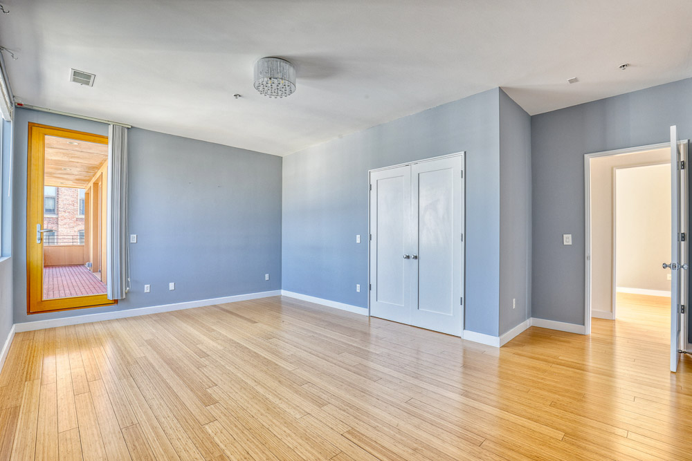 Bedroom before renovation with light wood floors, blue walls and natural light.