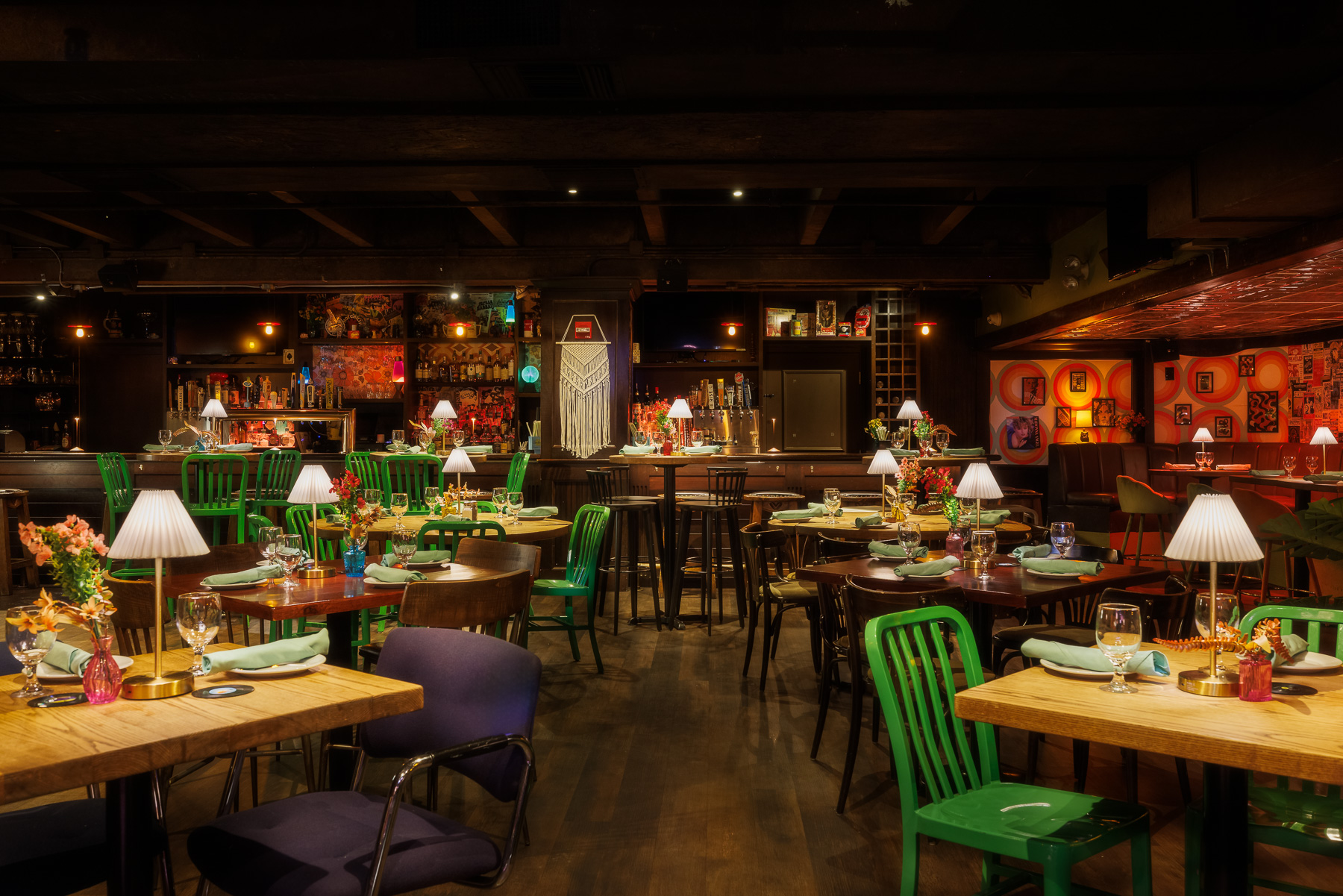 Dining room layout at Back Bay Social Boston featuring green chairs, wood tables, and layered ceiling details