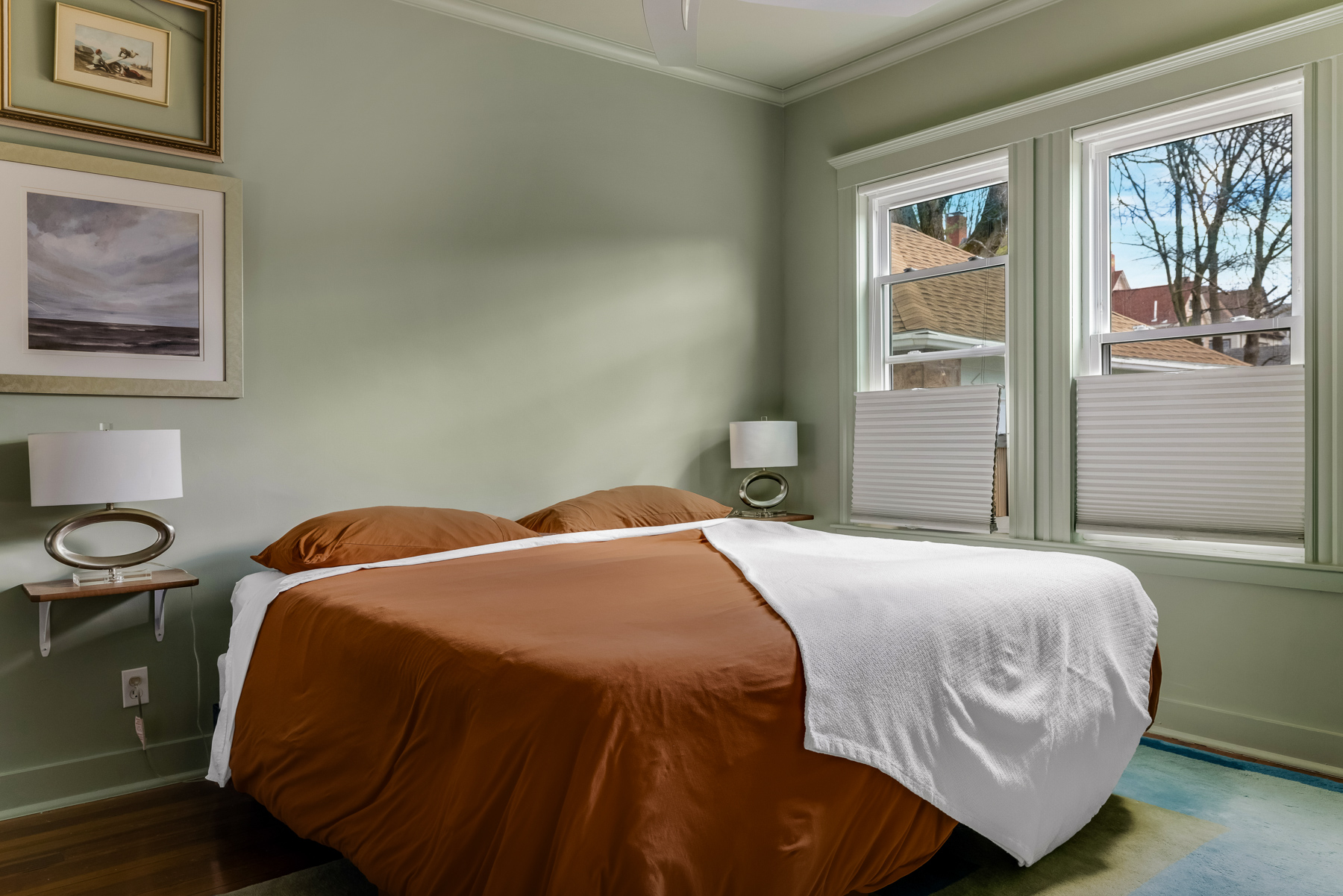 Bedroom with green walls, large windows, and hardwood floors in Airbnb