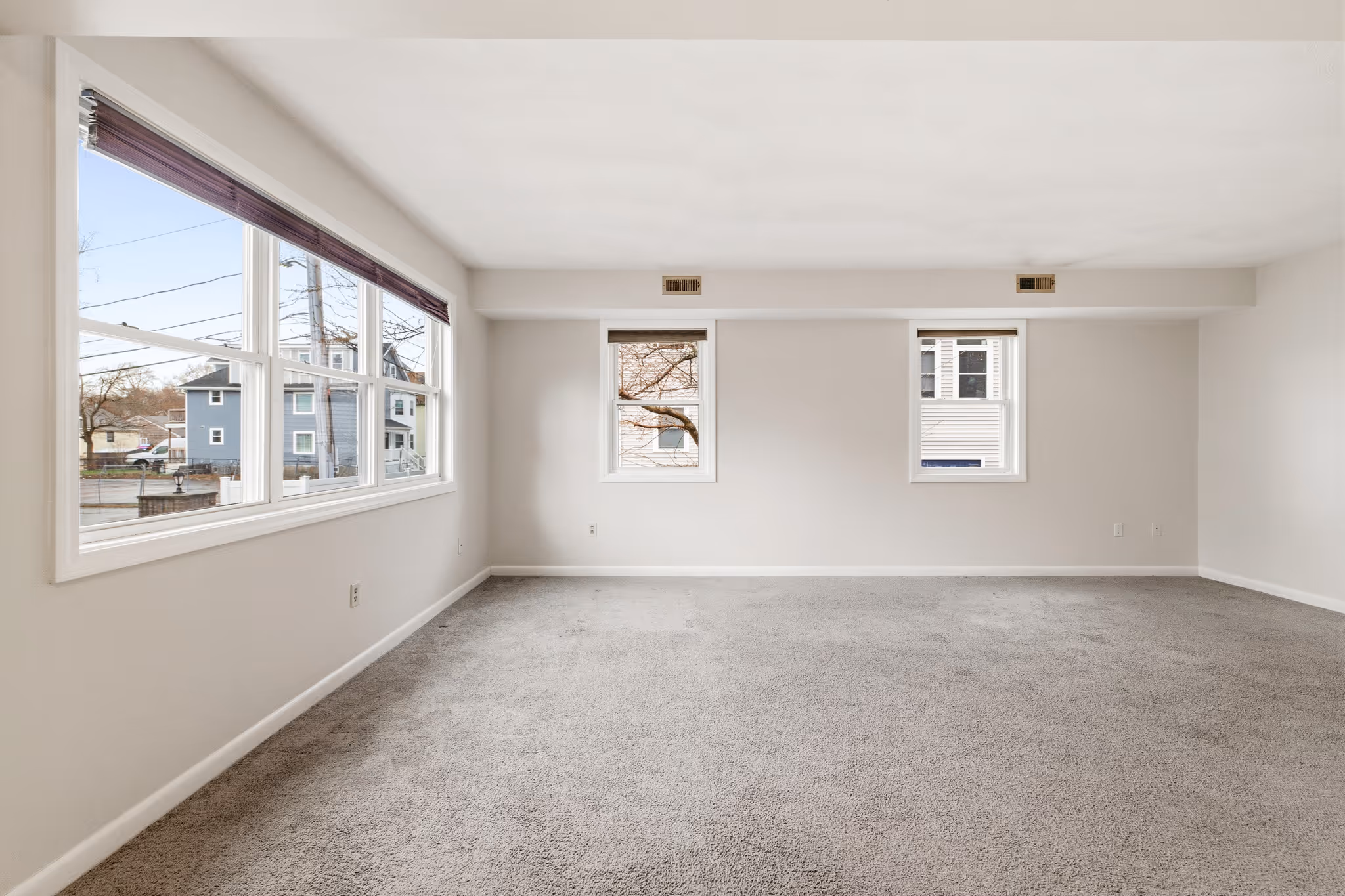 Open living room with multiple windows and clean layout in Boston condo