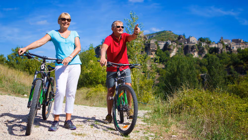 A man and a woman cycling together, smiling as they ride through a park.