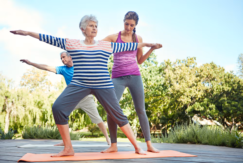 An older woman and a young woman practicing yoga together in a serene indoor setting, focusing on their poses.