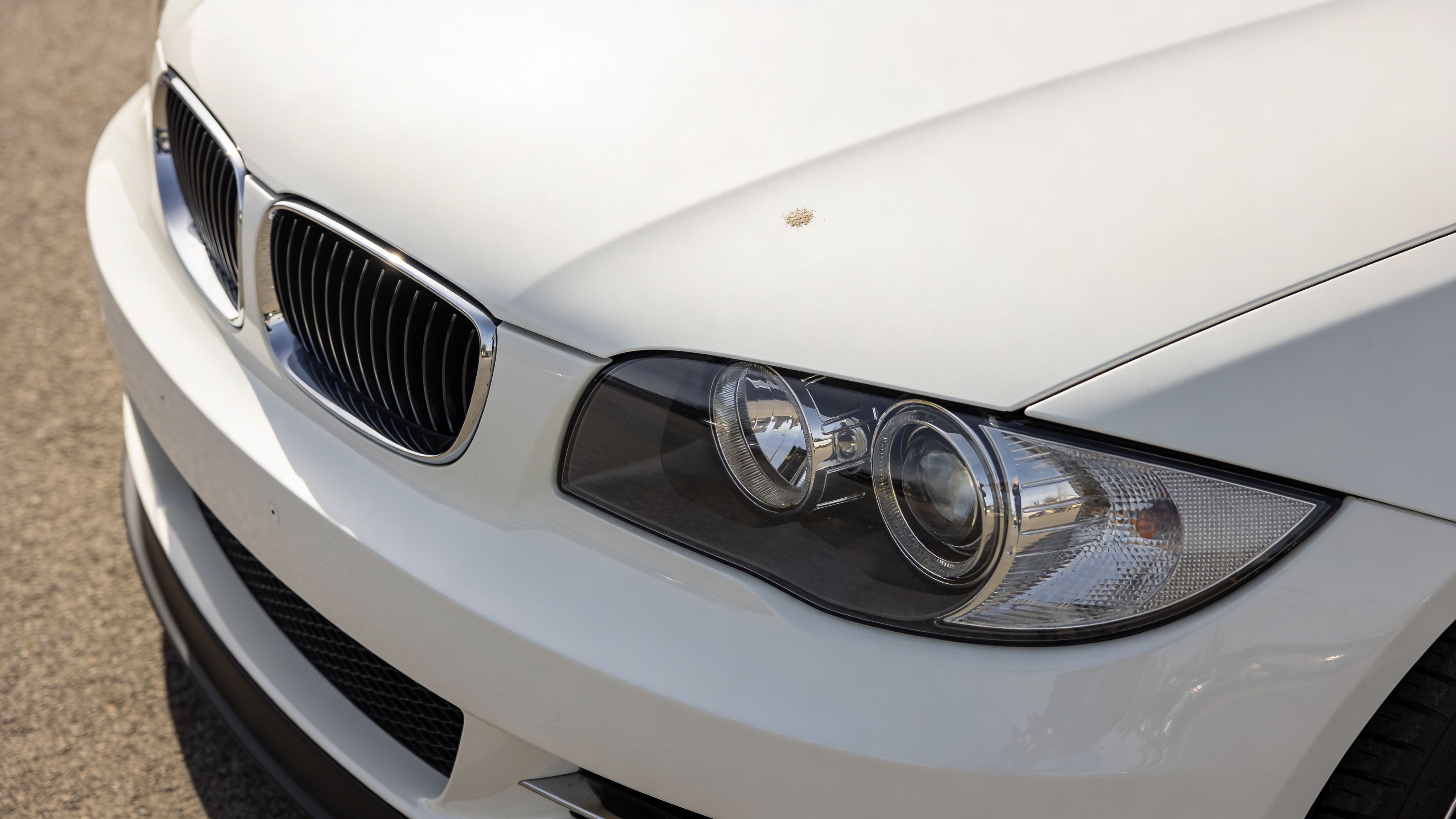 A close-up shot of the front of a clean white BMW car parked on asphalt.
