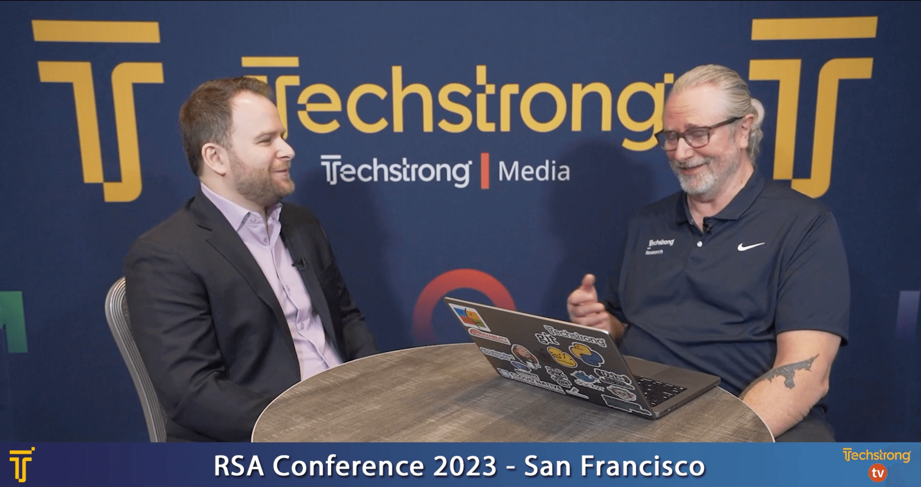 Illumio's Ben Harel and TechStrong TV's Mitch Ashley talking together at a table