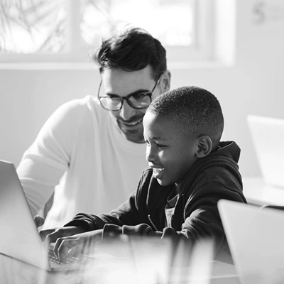 An educator working with a student on a laptop