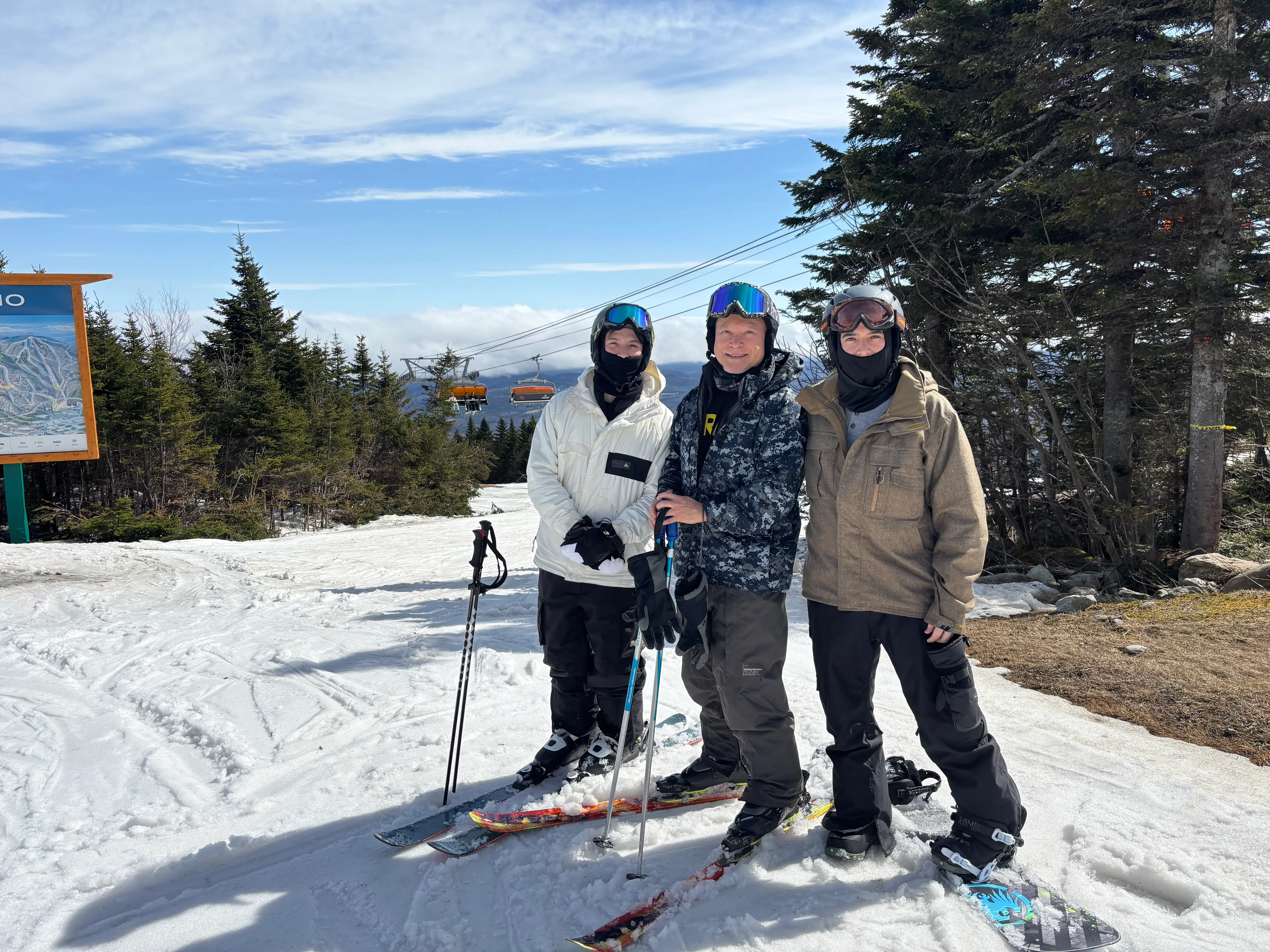 Father and sons skiing and snowboarding in early March in Okemo, Vermont.