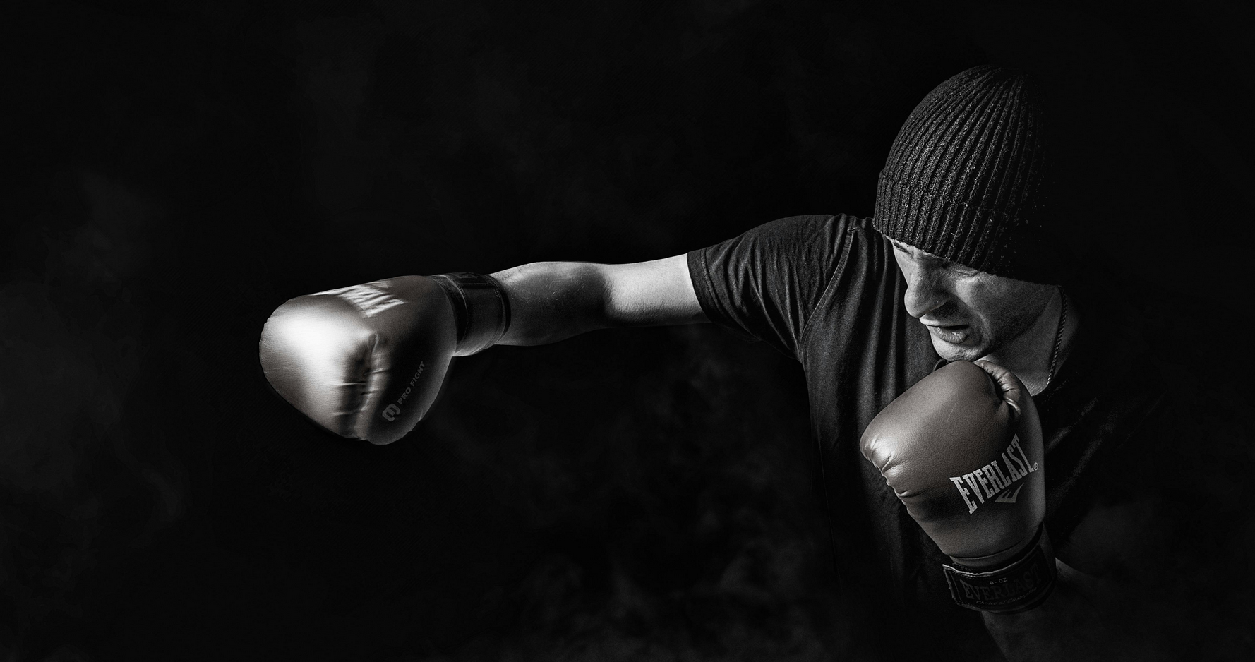 Landing image, male boxer wearing boxing gloves delivering a right hook.