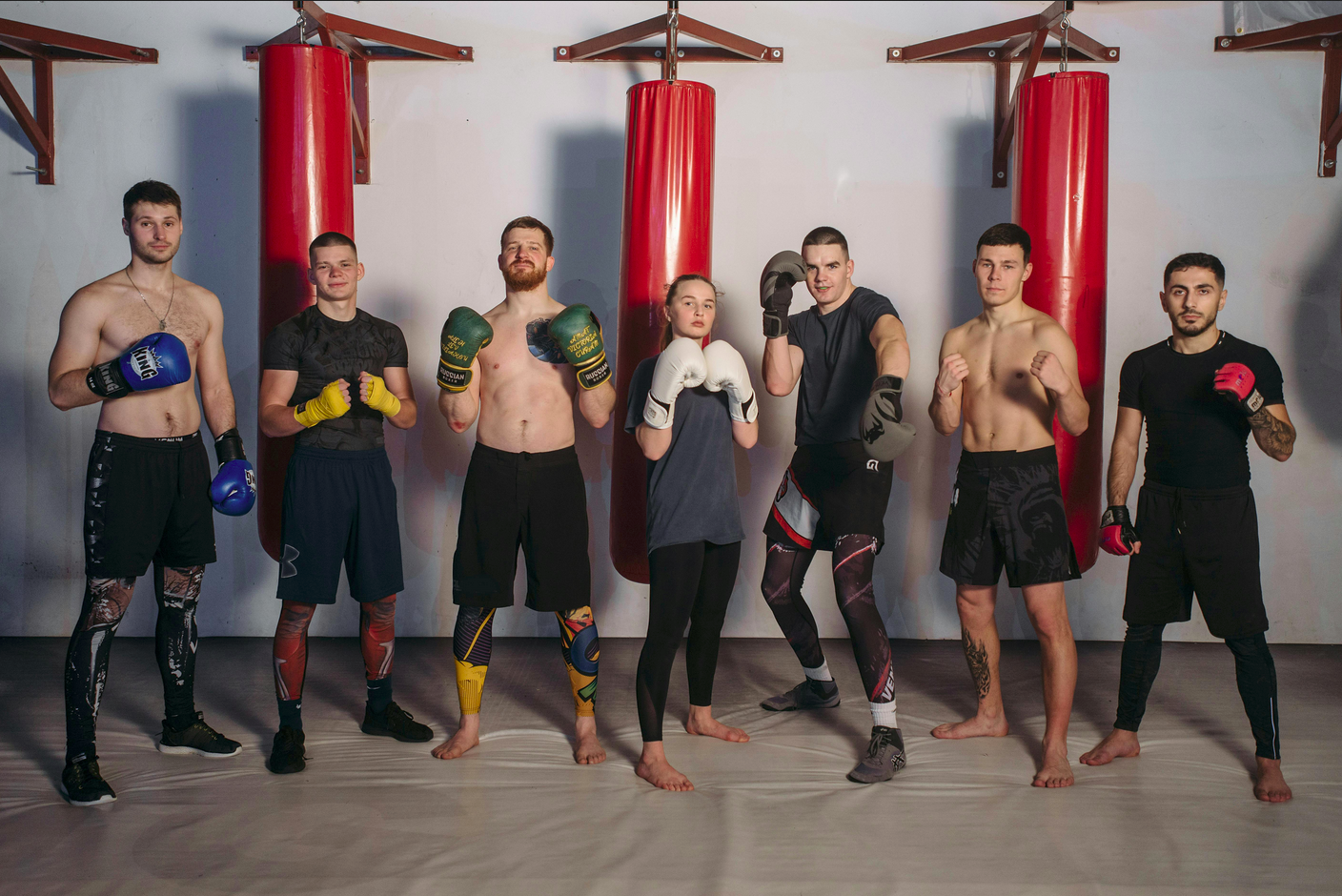 Group of people in front of punching bag in boxing poses.