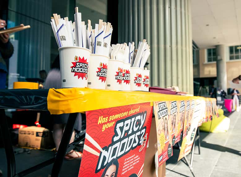 Photo of a table outside with Spicy Noods branded materials on it