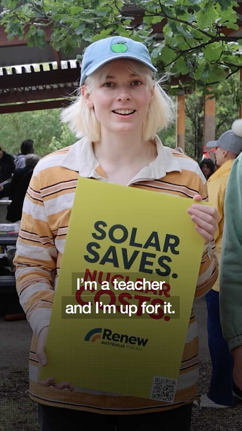 A still from a video for the Renew Australia for All campaign showing a woman holding a sign that says ‘solar saves’, captioned “I’m a teacher and I’m up for it.”