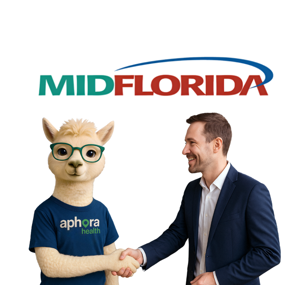 A man in a suit shaking hands with a friendly alpaca mascot named Nora wearing glasses and an Aphora Health t-shirt.