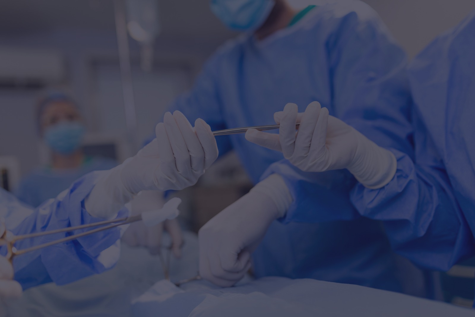 Medical professional in blue scrubs examining a patient's bent knee on an exam table.