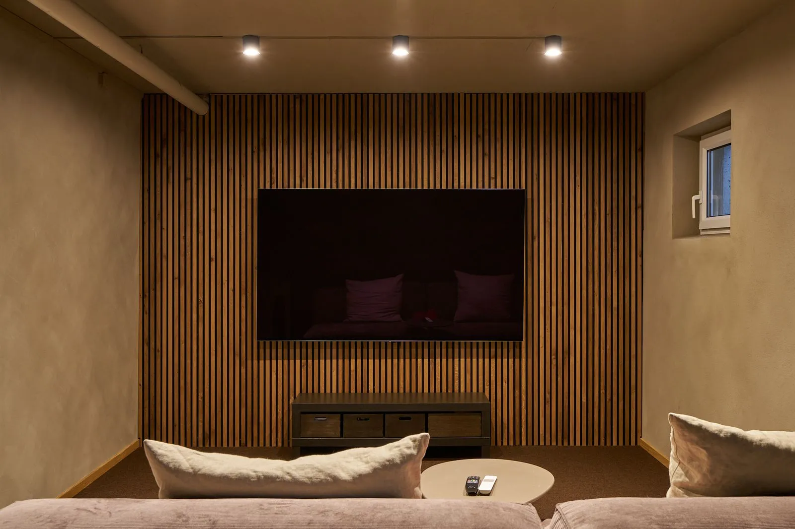 Moderner Wohnraum mit Holzlamellen, Fernseher und gemütlicher Sitzecke