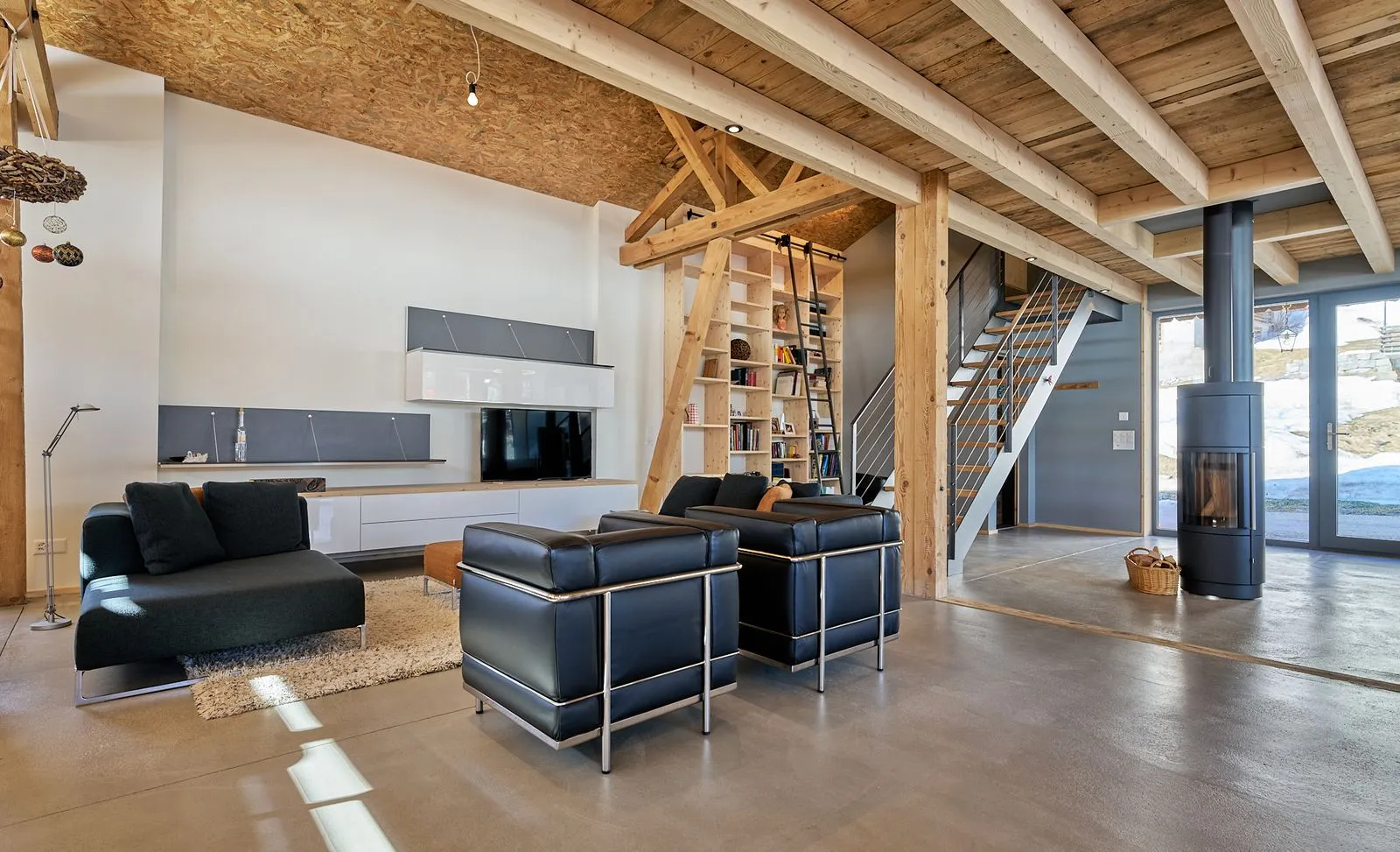 Modernes Wohnzimmer mit Holzbalken, schwarzen Möbeln und Kaminofen