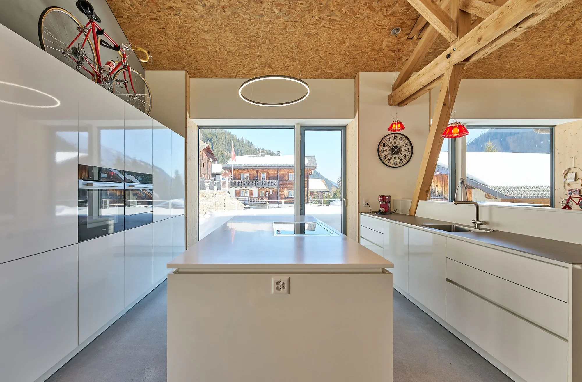 Moderne Küche mit Kochinsel, Fahrrad und Bergblick durch große Fenster