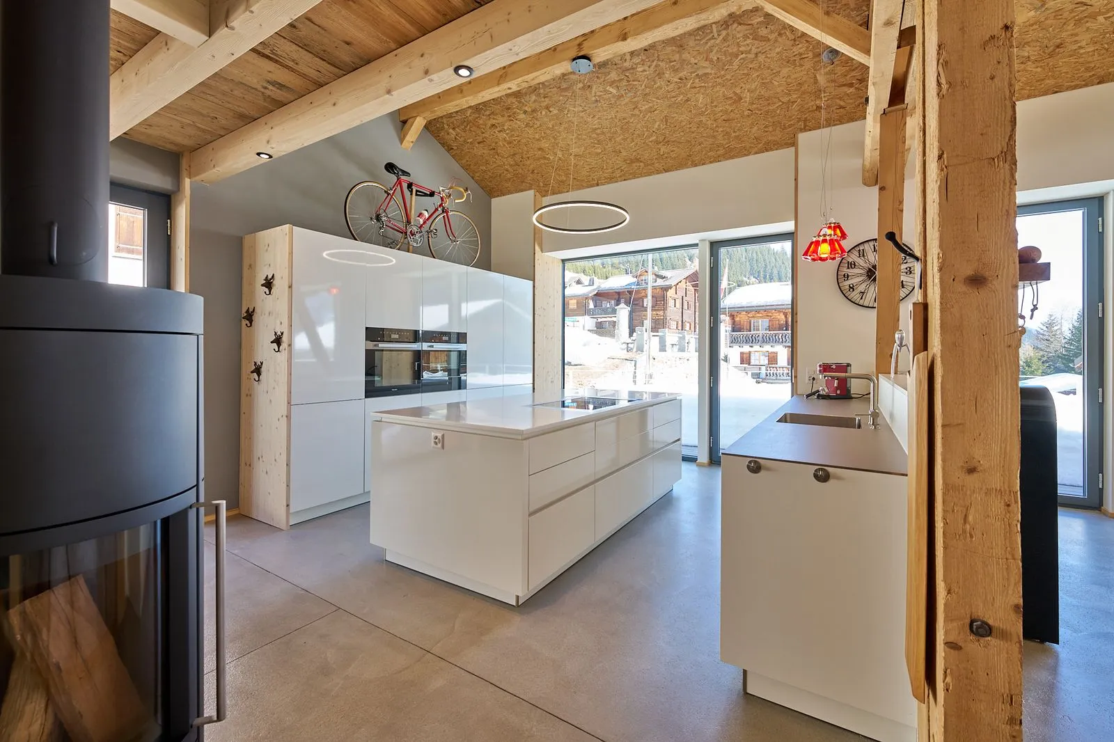 Moderne Bergküche mit weißer Insel, Holzbalken und rotem Fahrrad
