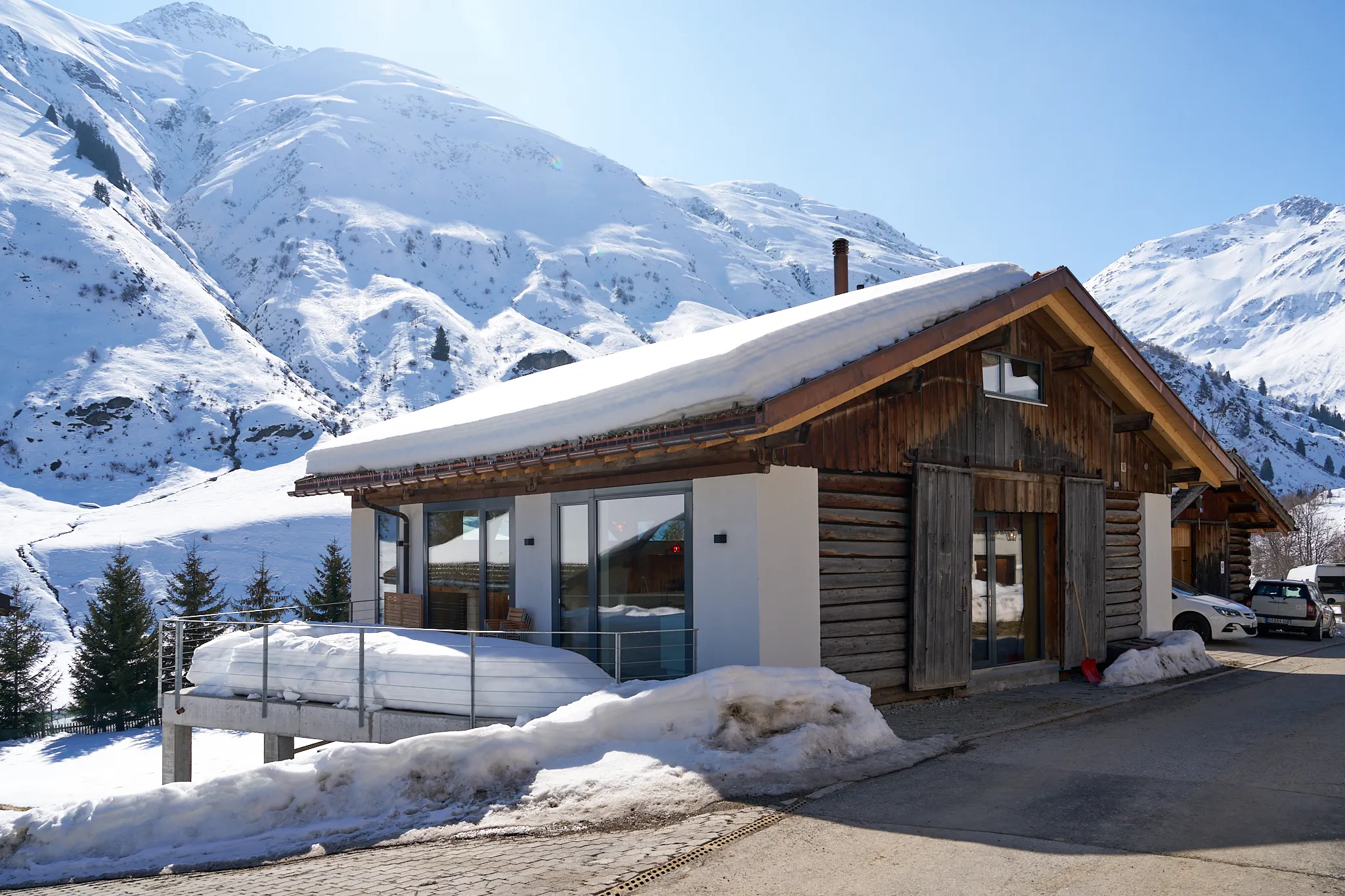 Modernes Holzhaus mit Glasfassade in verschneiter Berglandschaft