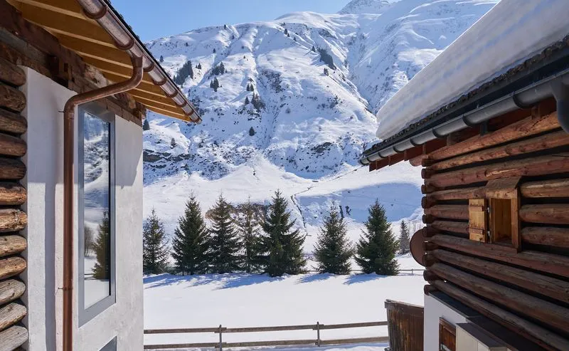 Verschneite Berghütten mit Blick auf majestätische Winterlandschaft mit Tannen