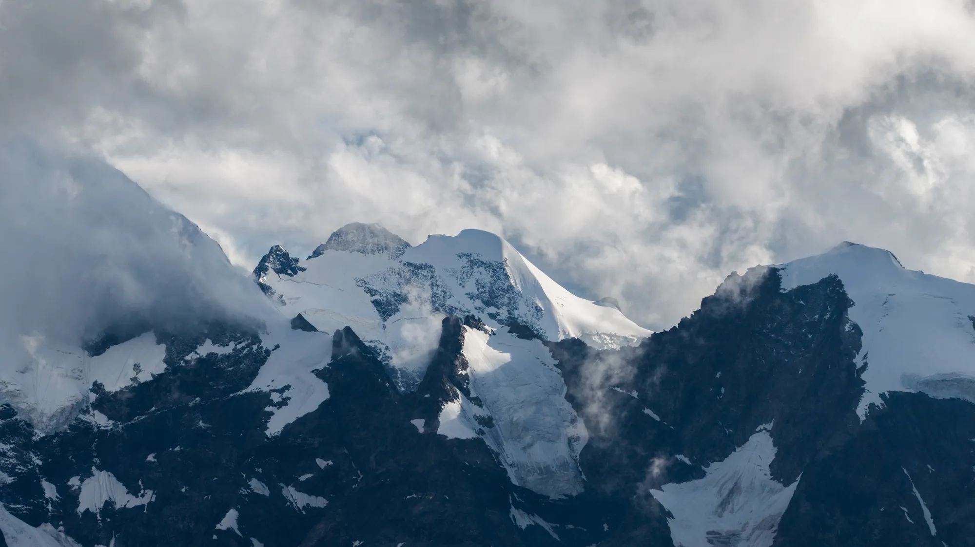 Schneebedeckte Berggipfel mit Wolken umgeben.