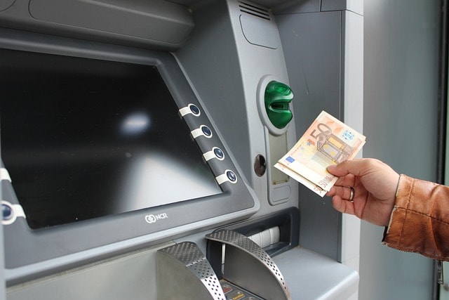 Auszahlung von Geld am Geldautomaten. Eine Person hält 50€ Scheine in der Hand.