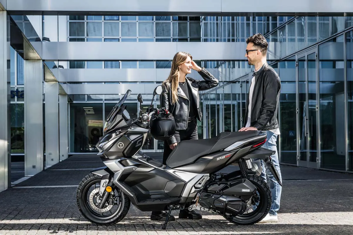 VOGE SR180 ADV scooter in front of a modern glass building with two people beside it.