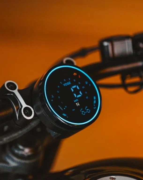 Close-up of the Voge CU250 digital speedometer against an orange background.