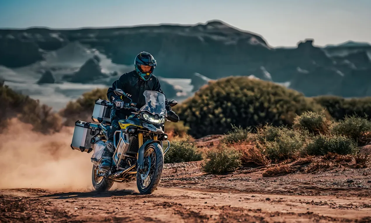 Rider taking the VOGE DS900X on rugged off-road terrain, kicking up dust