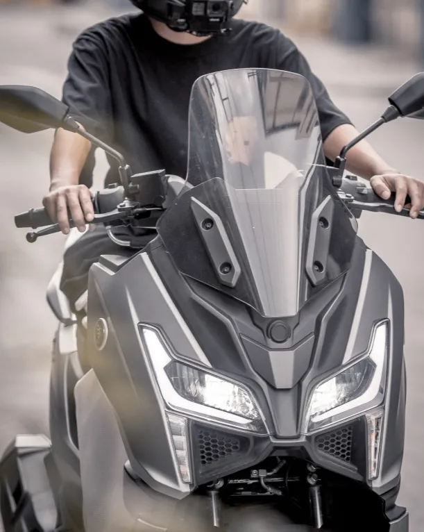 Rider on the Voge SR150GT scooter wearing a helmet, showcasing the front windscreen and controls