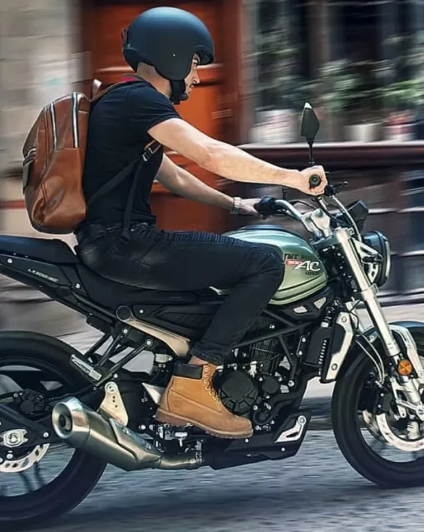 Motorcyclist riding the Voge 300AC on the road wearing a helmet and casual gear.