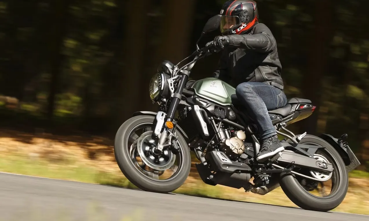 Rider on a black Voge 300AC motorcycle leaning into a curve on the road.