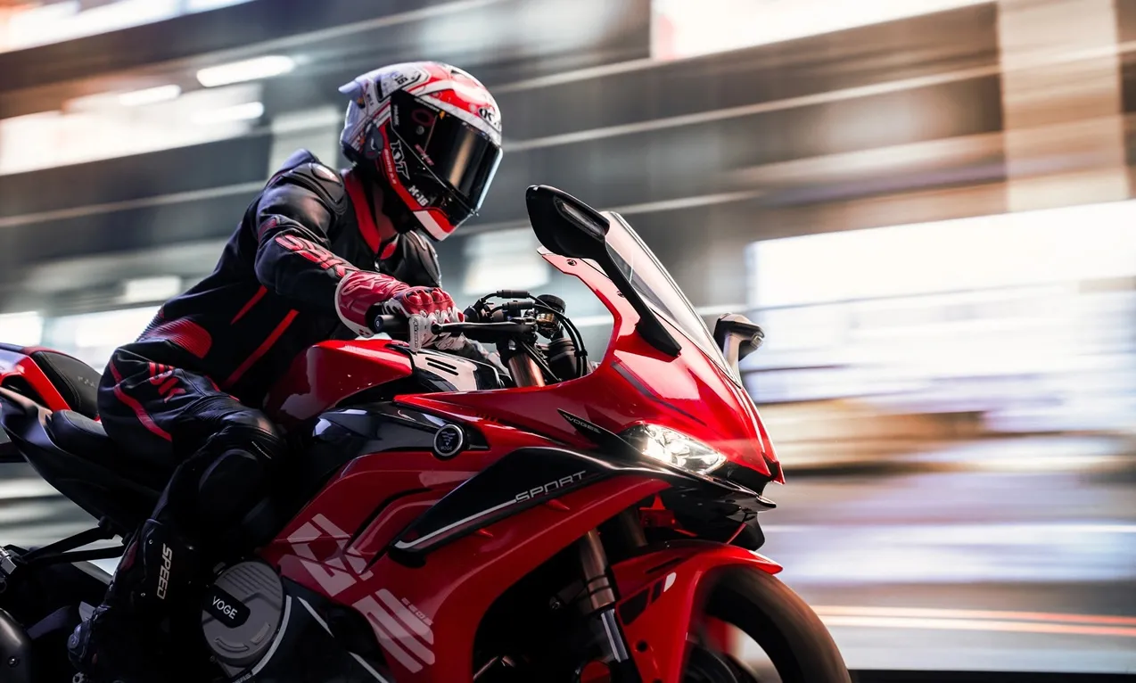Red VOGE RR660S speeding through a city road at night with skyscrapers in the background.