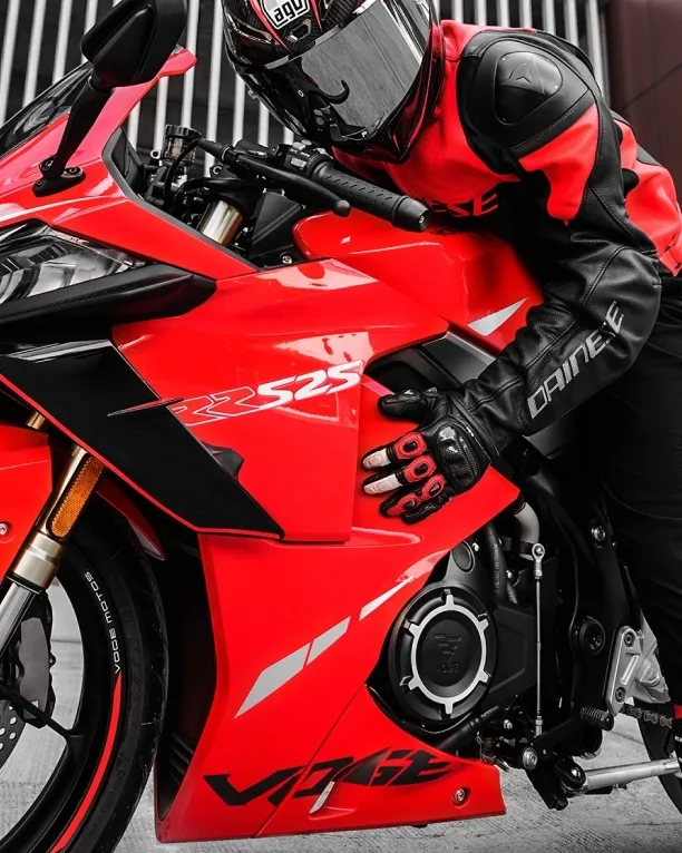 Rider leaning on a red VOGE 525RR sportbike, showcasing its aggressive design.