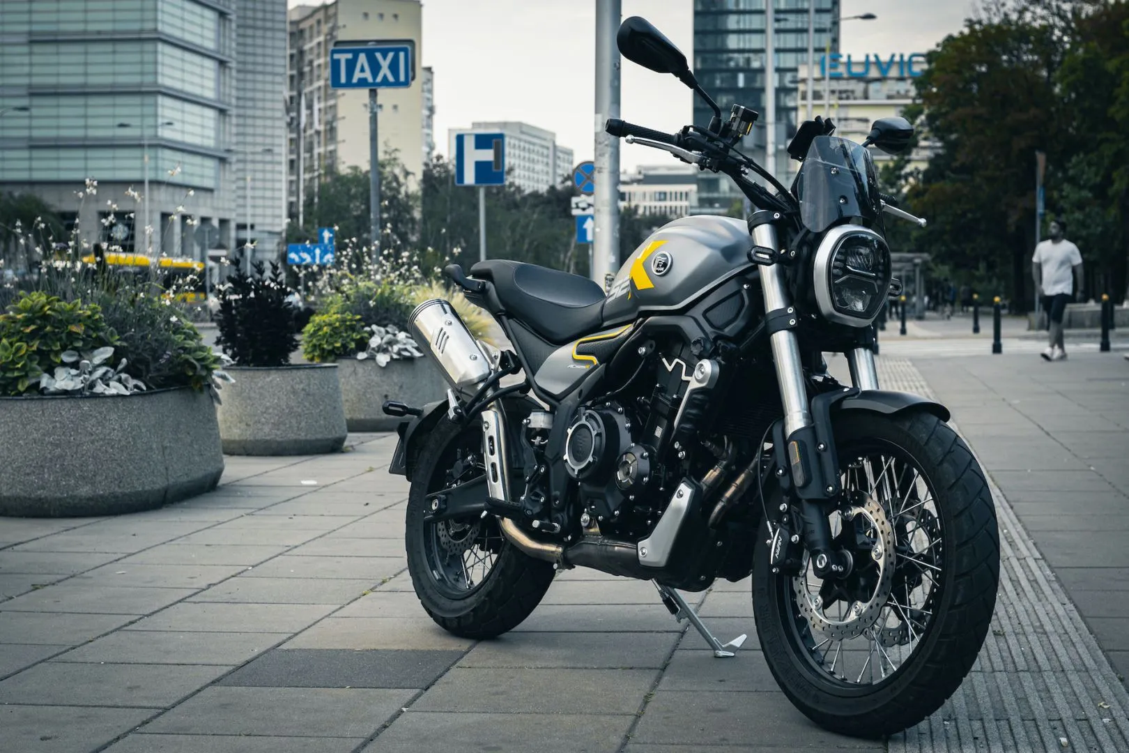 Side view of the Voge 525ACX motorcycle parked in a modern city setting with buildings in the background.