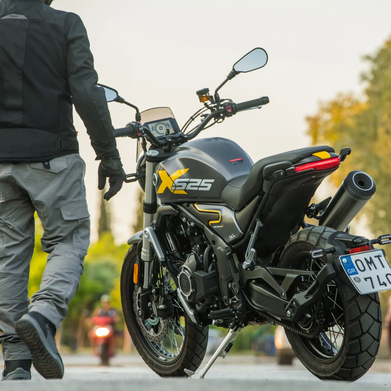 Rear-side view of the Voge 525ACX motorcycle with a rider standing beside it, ready to mount.