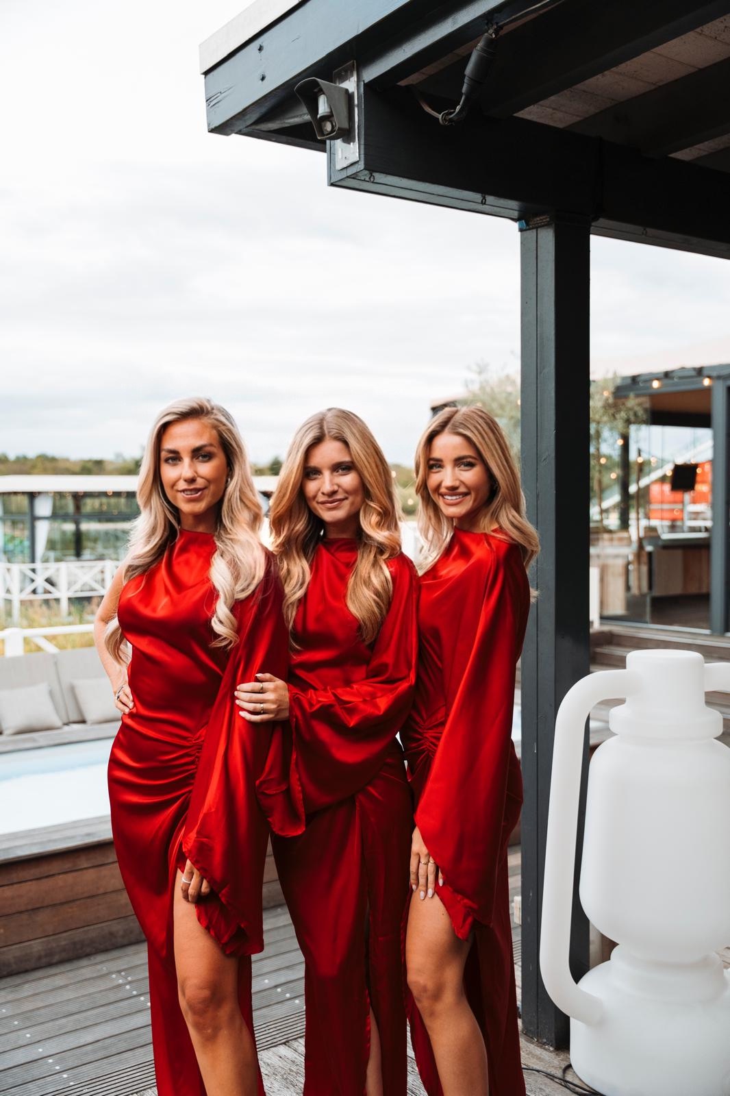 3 vrouwen in rode jurken die aan het poseren zijn