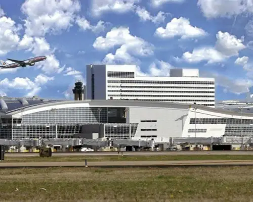 Modern airport terminal with airplane taking off against cloudy blue sky