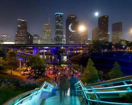 Houston skyline at night with illuminated bridge and crowded park